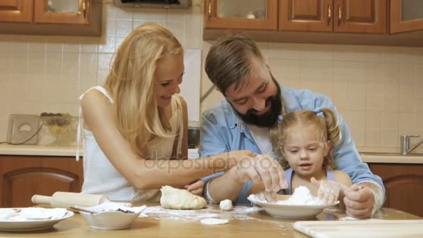 Mãe de família feliz, pai e filha pequena na cozinha preparando tortas do teste . — Vídeo de Stock