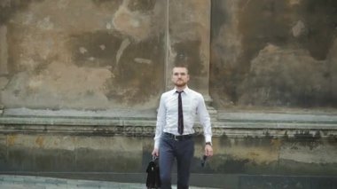 İşyeri kravatını sabitleme binasının önünde bir çanta ile ciddi iş adamı