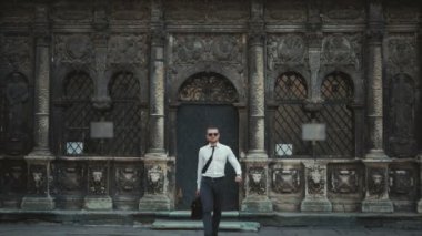 İşyeri kravatını sabitleme binasının önünde bir çanta ile ciddi iş adamı