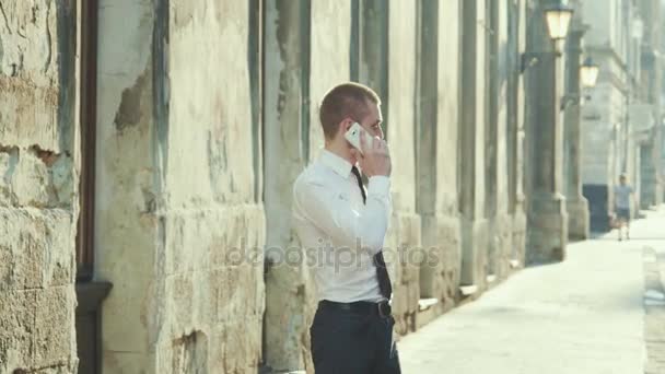Empresario con un maletín charlando en un teléfono móvil — Vídeos de Stock
