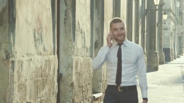Empresario con un maletín charlando en un teléfono móvil — Vídeo de stock