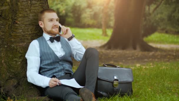 Uomo in un parco verde che parla al telefono — Video Stock