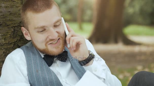 携帯電話で話している緑豊かな公園の男 — ストック動画