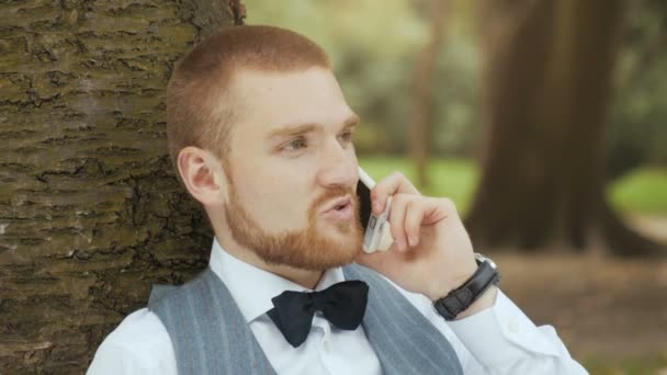 Homme dans un parc vert parlant au téléphone — Video
