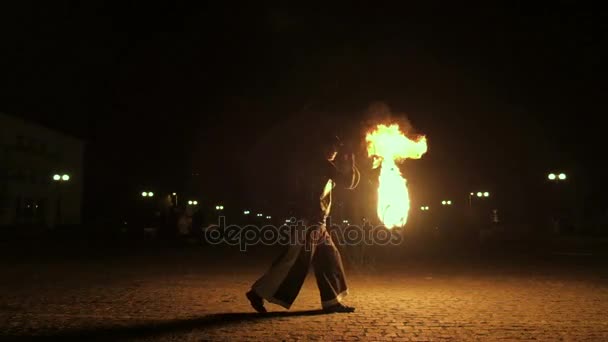 Fire show performance. Handsome male fire juggler performing contact manipulation with fire baton with several wicks dragon staff. Close-up. Slow motion — Stock Video