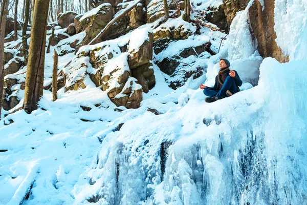 젊은 남자는 숲에 눈 눈 더미에 앉아서 겨울 강 보고 — 스톡 사진