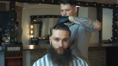 Kuaför siyah saçlı ve mavi gömlek ve siyah eldiven makas kuaför dükkanında, arka plan, ışıkları ile istemci için bir saç kesimi yapıyor dövme ile portre.