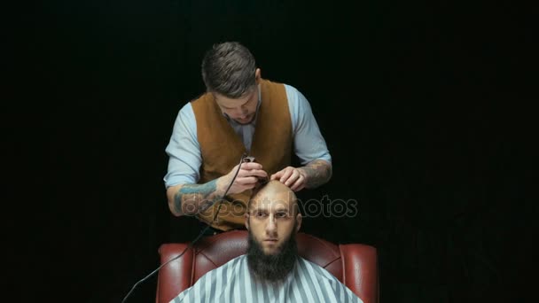 Zbliżenie: człowiek coraz włosy ogolone w trymer. Fryzjer ręka trzyma trymera elektrycznego i golenie głowy klientów. czarne tło — Wideo stockowe