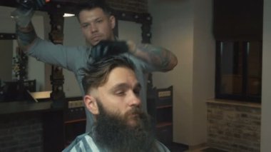 Siyah saçlı ve beyaz gömlek ve siyah eldiven makas kuaför dükkanında ile acımasız istemci için bir saç kesimi yapıyor dövme ile berber