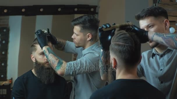 Nieuw kapsel. Zijaanzicht van jonge bebaarde man krijgen verzorgd bij Kapper met föhn zittend in de stoel bij barbershop — Stockvideo