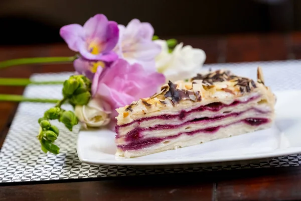 Blueberry vanília torta darab tortát a close-up virágok fehér lemez. — Stock Fotó