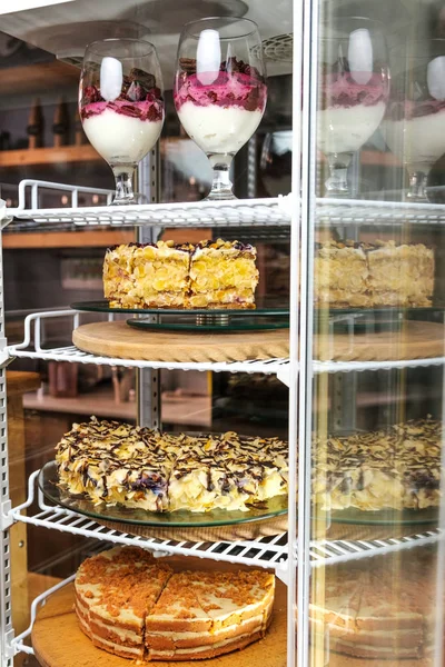 Kakebutikk en stor kake i et glassskap. Fargerike desserter stockfoto