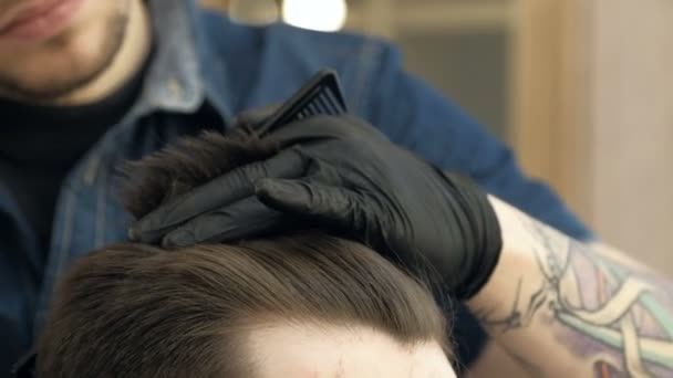 Master corta pelo y barba en la peluquería. Guantes negros con tatuajes fuera de las manos. de cerca — Vídeos de Stock
