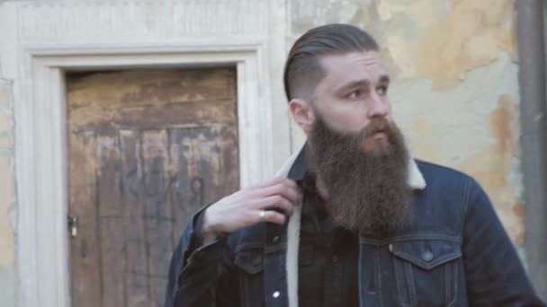 Портрет бородатого чоловіка з довгим волоссям, одягнений у джинсову куртку , — стокове відео