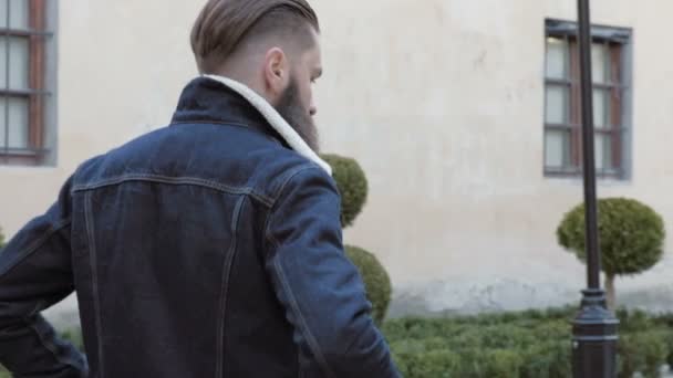 Portrét vousatého muže s dlouhými vlasy, oblečen v džínové bundě, — Stock video