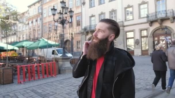 Retrato de un joven barbudo emocionado hombre feliz hablando con un amigo por teléfono — Vídeo de stock