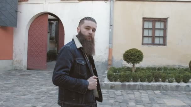 Красивый бородатый мужчина позирует на улице, жестокий хипстерский портрет — стоковое видео