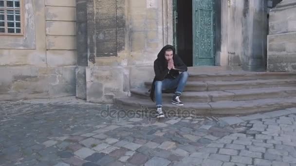 Bearded man, long beard, brutal hipster with moustache on serious Sits on the steps in the old building. — Stock Video
