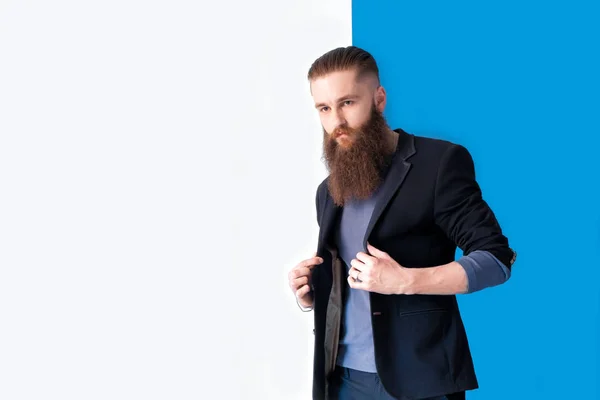 Retrato de um homem bonito vestido com jaqueta preta e jeans no fundo azul e branco — Fotografia de Stock