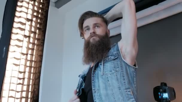 파란색 배경으로 스튜디오에서 남자 모델에 대 한 사진을 찍고 사진 작가. 긴 수염을 가진 남자 모델입니다. 패션 카탈로그 촬영 — 비디오