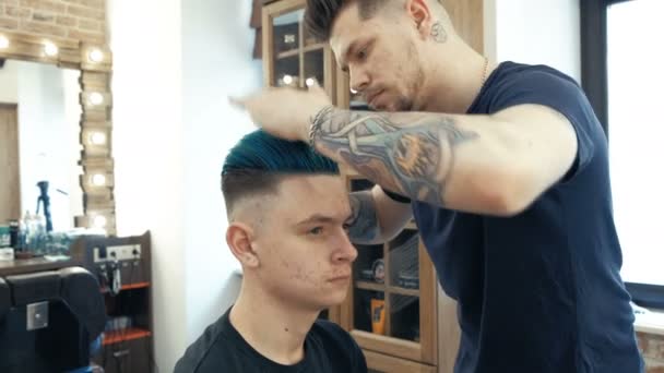 Maestro corta el pelo y la barba de los hombres en la peluquería, peluquería hace peinado para un hombre joven . — Vídeos de Stock