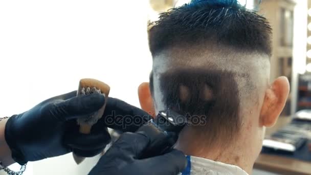 El peinado se ve fresco y divertido. Un joven barbudo es cortado por un peluquero, sentado en un sillón en una peluquería . — Vídeo de stock