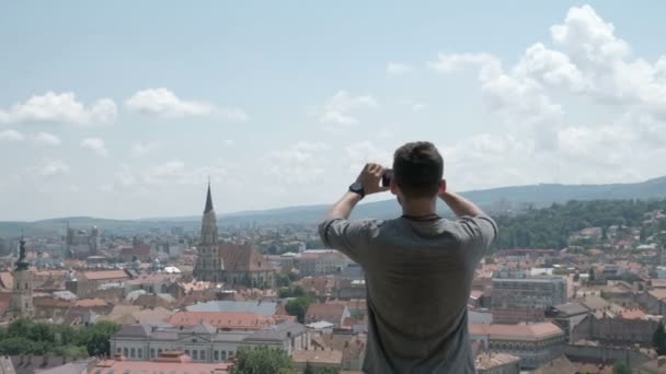 Hombre viajero hacer una foto panorámica de la ciudad vieja a su teléfono para Instagram u otras redes sociales. Viajar a Rumania . — Vídeo de stock