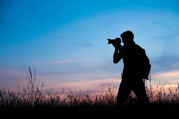 Silhouette of a young who like to travel and photographer, taking pictures of the beautiful moments during the sunset, sunrise . — стоковое фото