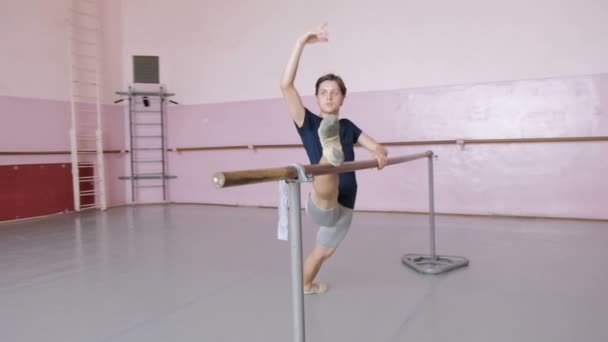 Junge männliche Balletttänzerin posiert in der Nähe von Barre, Mann übt Stretch im Tanzstudio — Stockvideo