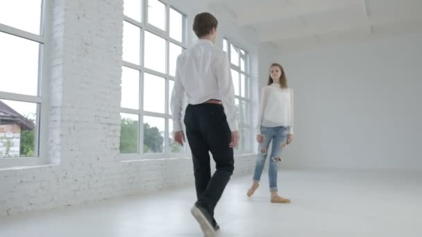 Пара молодых артистов балета, выступающих в белом зале — стоковое видео