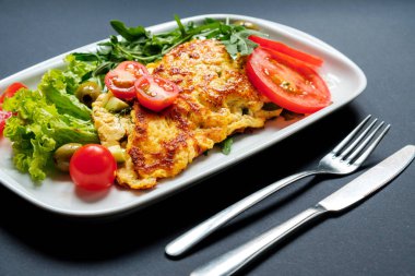 Domates ve rocula Kızarmış tofu salatası. Siyah bir arka plan üzerinde beyaz bir tabak içinde ev yapımı vejetaryen salata. Asya diyet sağlıklı vegan vejetaryen salata.