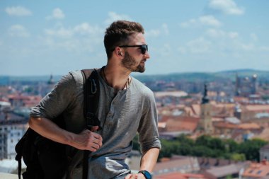 Adam seyahat etmek sırt çantası ile şehir ve sahil panoramik manzaraya bakarak şehir araştırıyor. Seyahat kavramını yeni yerler keşfetmek