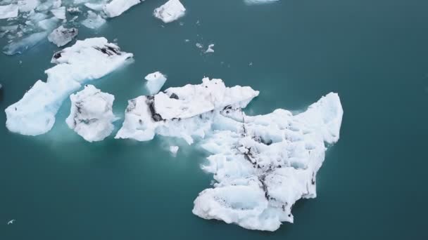 Aéreo sobre icebergs flutuando na Lagoa Jokulsarlon pela costa sul da Islândia — Vídeo de Stock