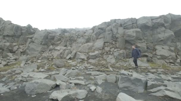 Hombre caminando sobre rocas en lo alto de las montañas — Vídeos de Stock