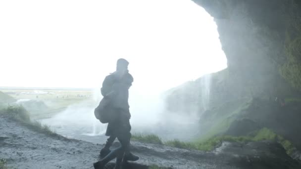 Paar steht auf einem Hügel am Wasserfall. Silhouette eines Paares hält Händchen — Stockvideo