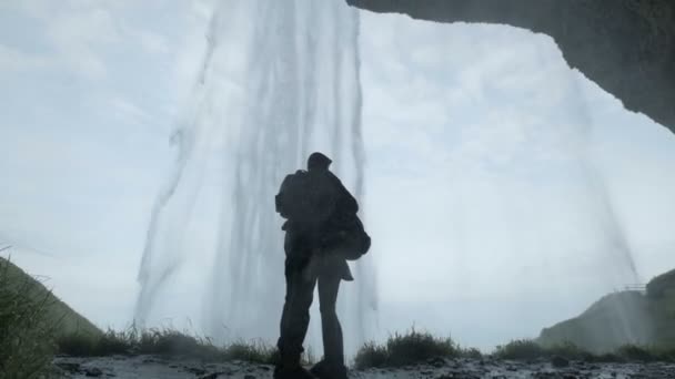 Staande op de heuvel bij waterval (echt) paar. Silhouet van een paar houdt handen — Stockvideo