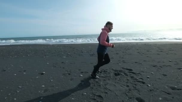 Jovem e bonito homem correndo na areia do mar . — Vídeo de Stock