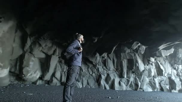 Young bearded man standing alone in a cave of Iceland. — Stock Video