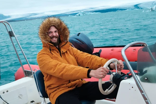 Onnellinen mies veneessä Joculsarlonin jäisellä laguunilla Islannissa — kuvapankkivalokuva