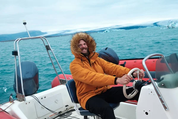Happy man on a boat on the icy lagoon of Joculsarlon, Iceland