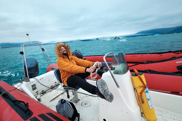 Onnellinen mies veneessä Joculsarlonin jäisellä laguunilla Islannissa — kuvapankkivalokuva