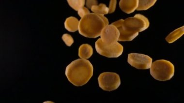 siyah bir zemin üzerine düşen havuç dilimleri. Makro