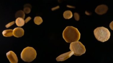 siyah bir zemin üzerine düşen havuç dilimleri. Makro