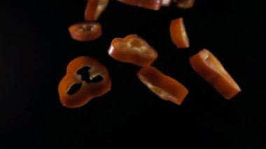 Kırmızı Pul Biber uçan ile yaratıcı bir konsept. İzole kayan biber dilimlenmiş. Düşüncesizlik kırmızı biber sebze siyah arka plan üzerine izole. Makro