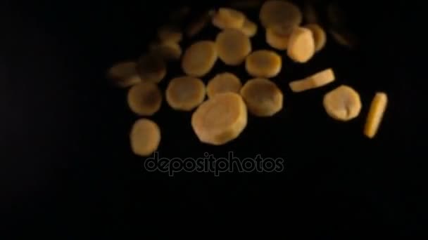 Falling carrot slices on a black background. macro — Stock Video