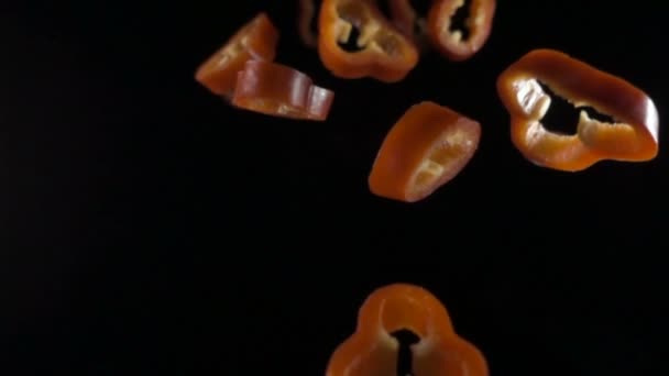 Creatief concept met vliegende rode paprika. Gesneden zwevende peper geïsoleerd. Lichtzinnigheid capsicum plantaardige geïsoleerd op zwarte achtergrond. macro — Stockvideo