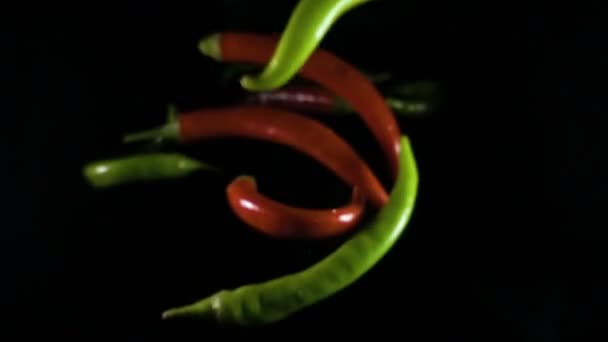 Red and green chili peppers on black background — Stock Video