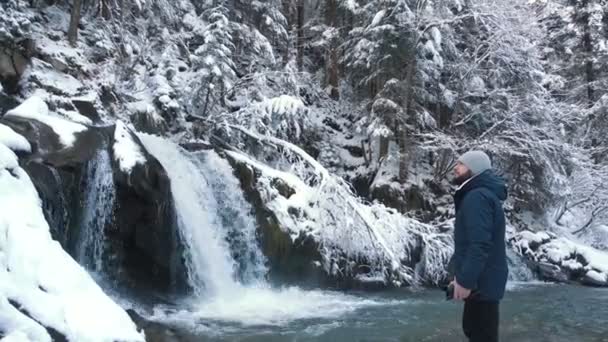 Мужской турист, зимний водопад в лесу с сосульками и снегом — стоковое видео