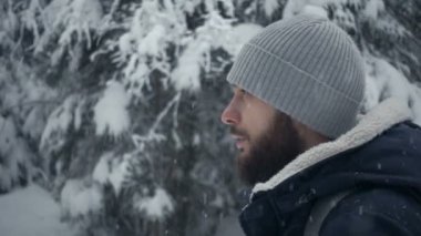 Kış ormanda ayakta neşeli sakallı yakışıklı genç portresi. Ağır çekim