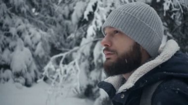 Kış ormanda ayakta neşeli sakallı yakışıklı genç portresi. Ağır çekim